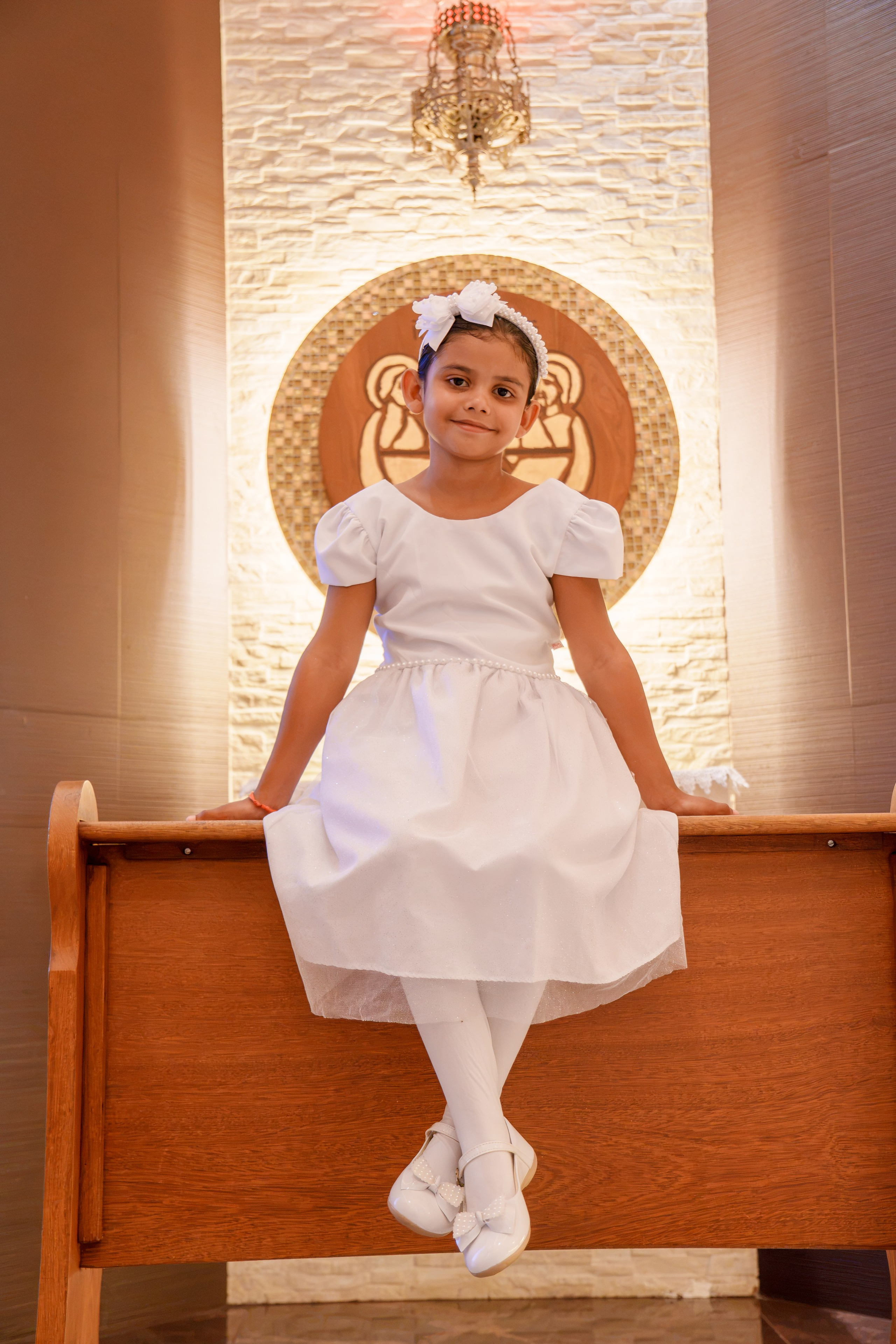 Menina vestida de branco caminhando durante celebração do batismo