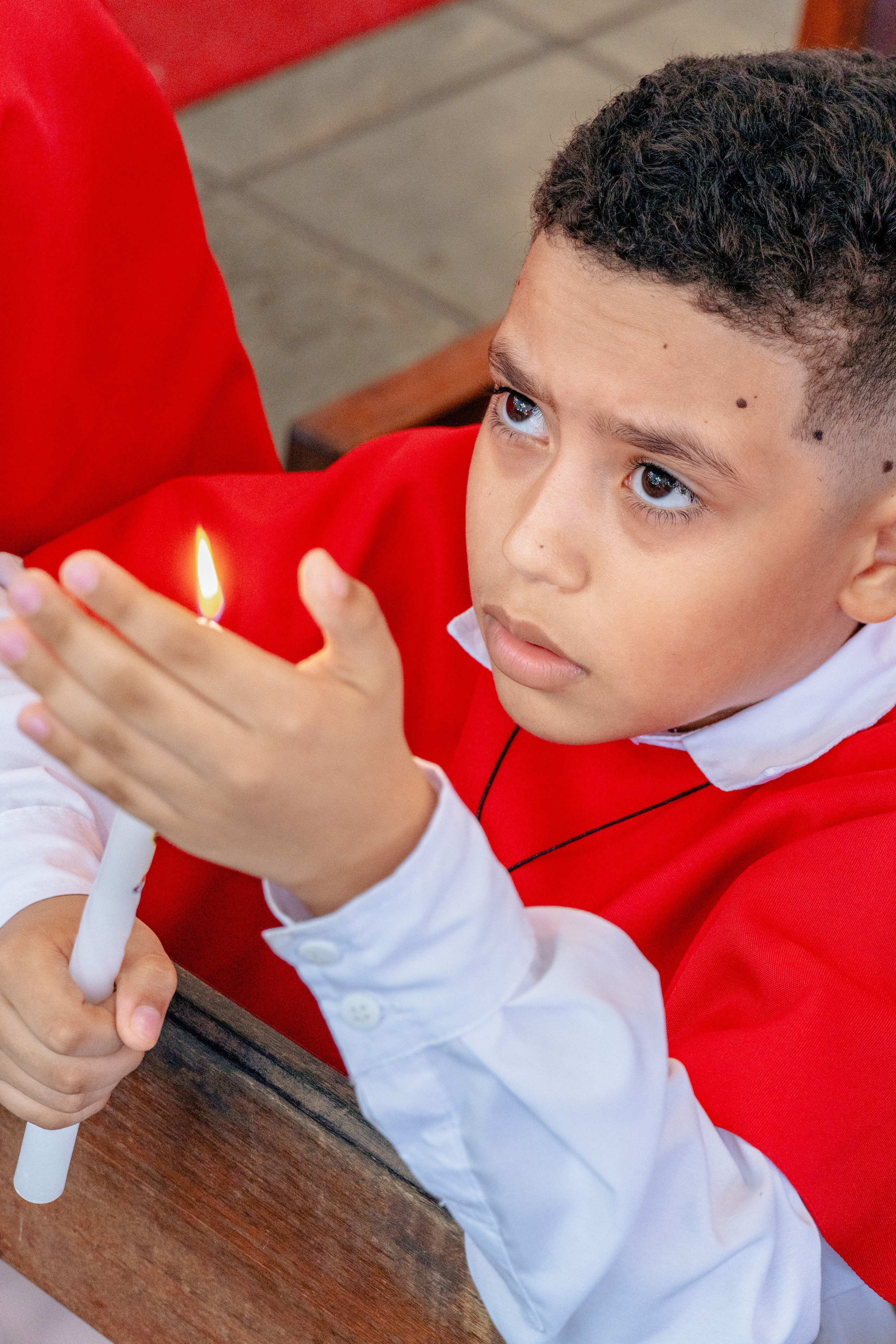 Criança segurando elemento litúrgico durante celebração de Primeira Eucaristia