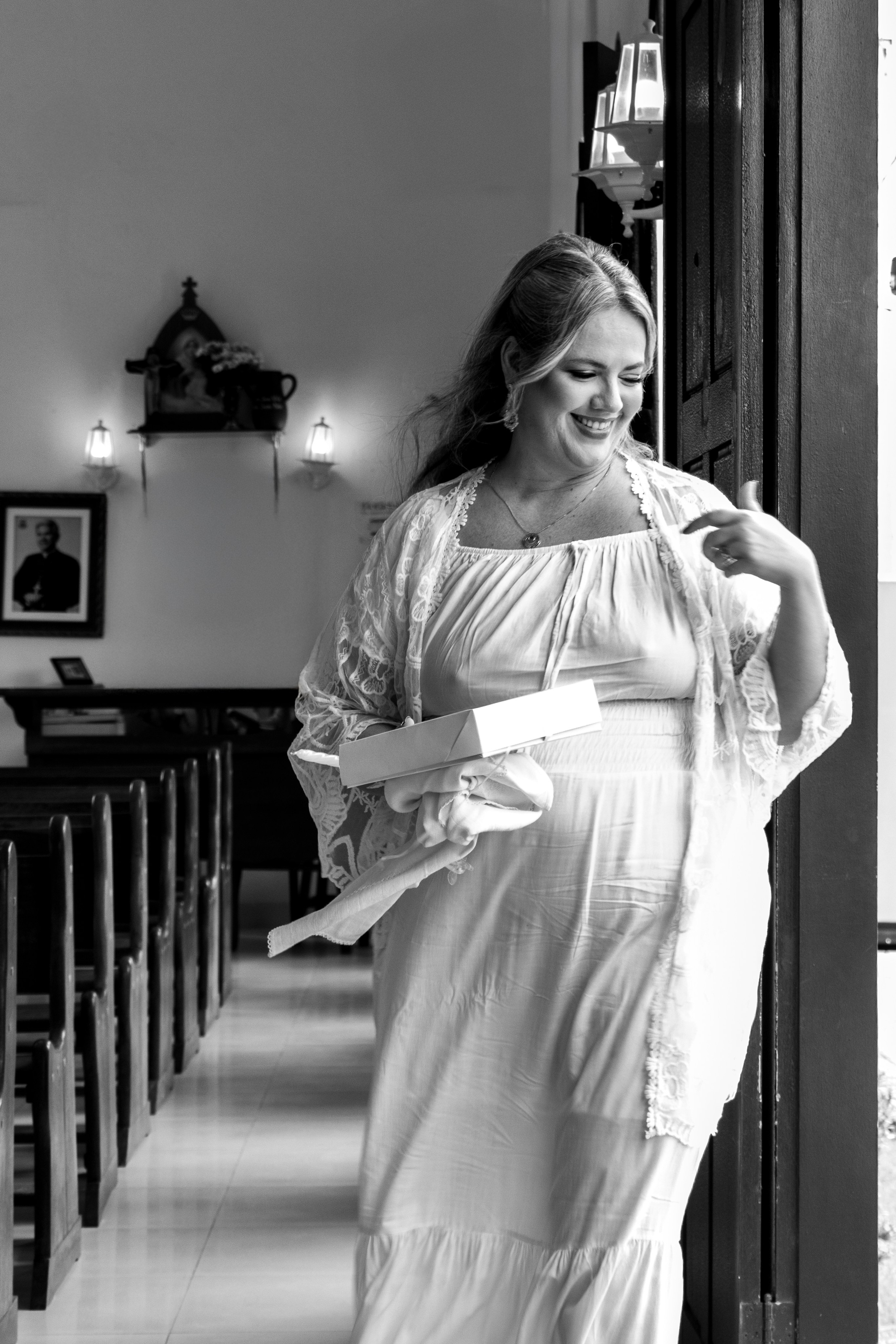 Mãe gestante caminhando pelo corredor da igreja durante cerimônia de batismo do filho
