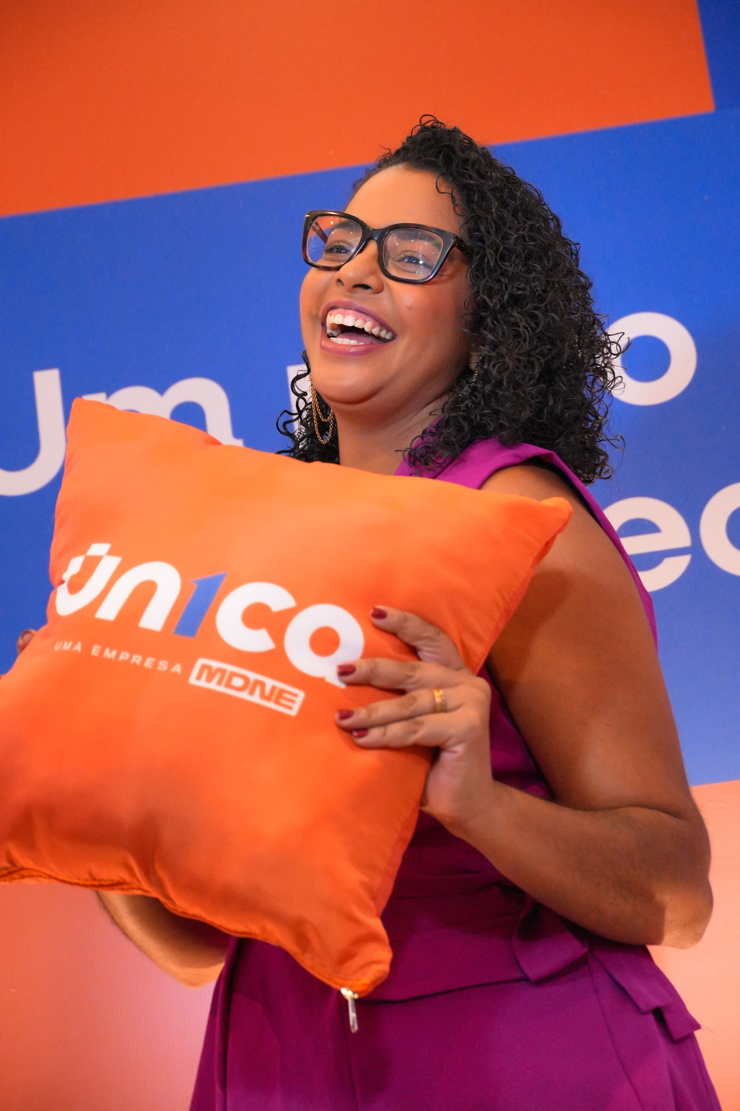Mulher sorrindo enquanto segura almofada durante lançamento da ação ou evento Un1ca