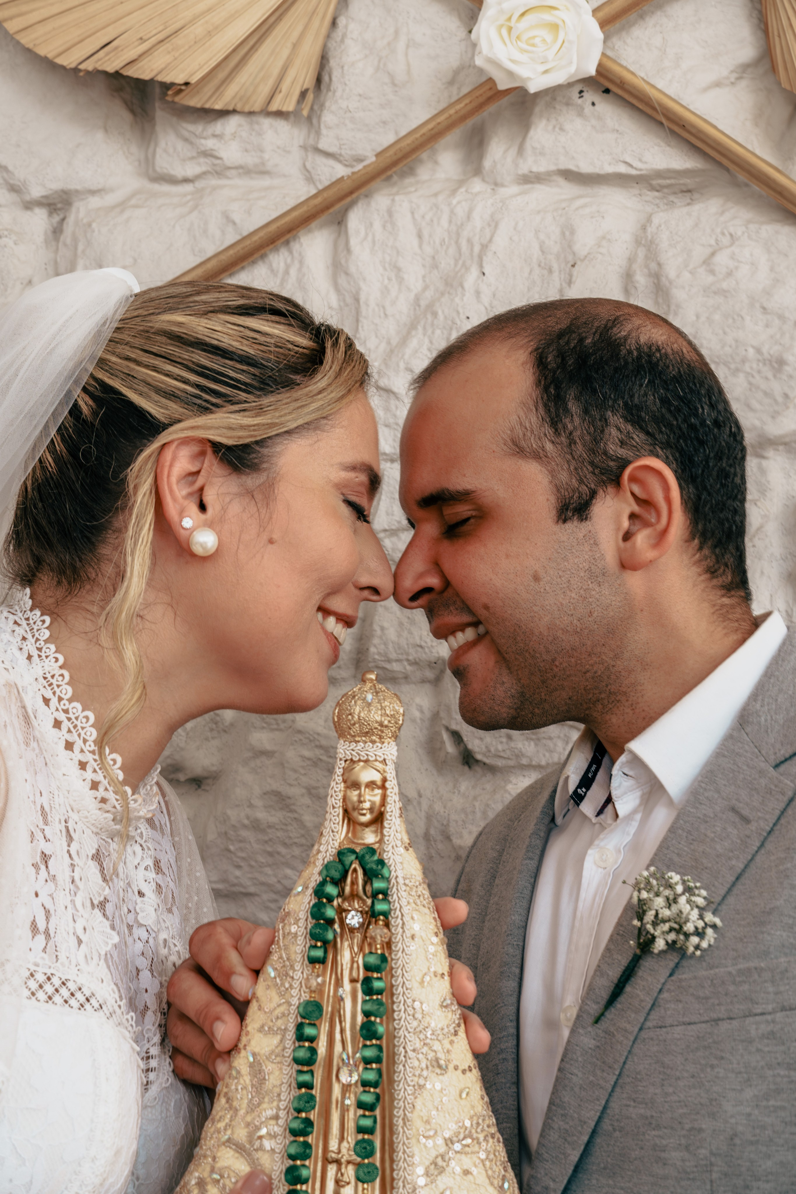 Noivos próximos durante cerimônia religiosa com imagem de Nossa Senhora