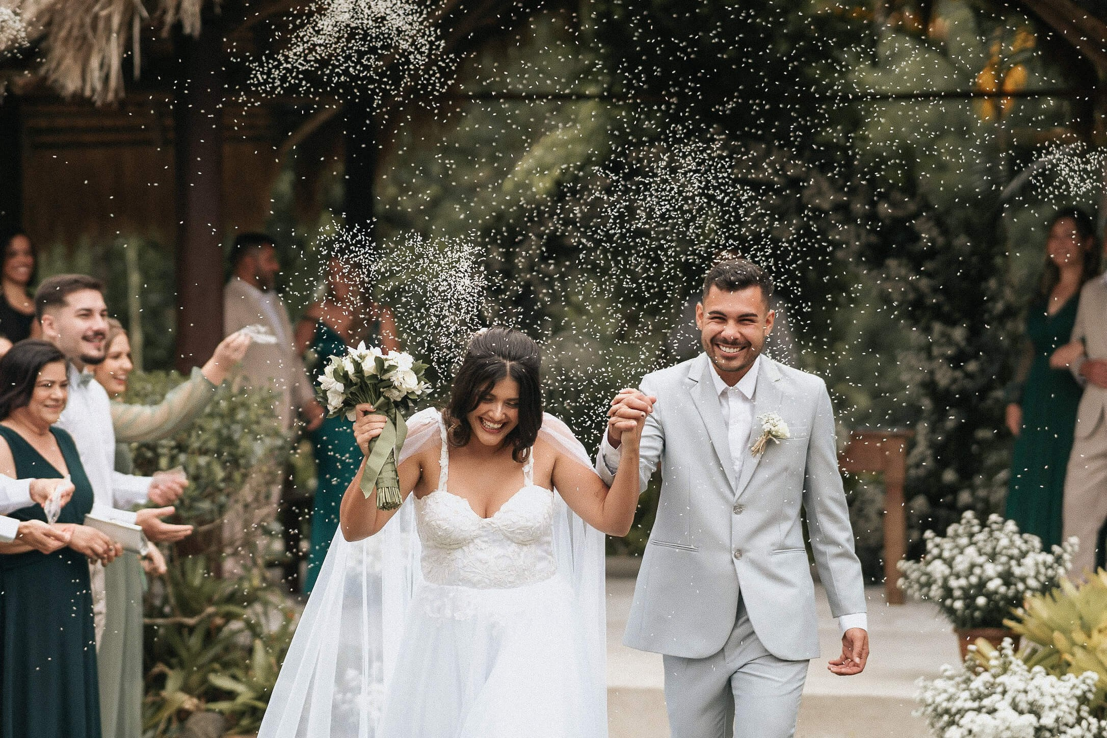 Bride and groom celebrating with rice toss during wedding in Rio de Janeiro, joyful destination wedding in Brazil.