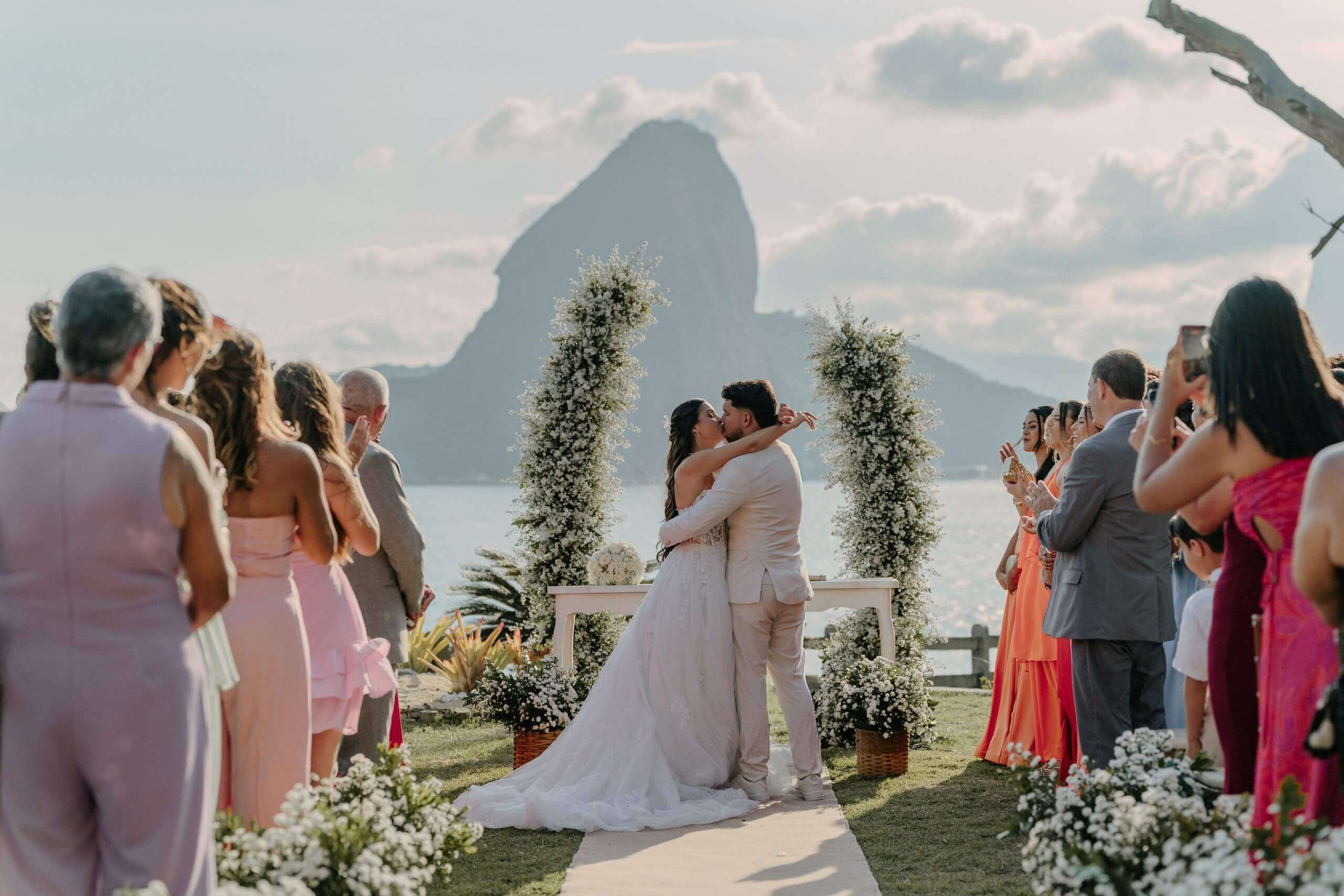 Couple kissing during outdoor wedding ceremony with Sugarloaf Mountain view in Rio de Janeiro, romantic destination wedding in Brazil.
