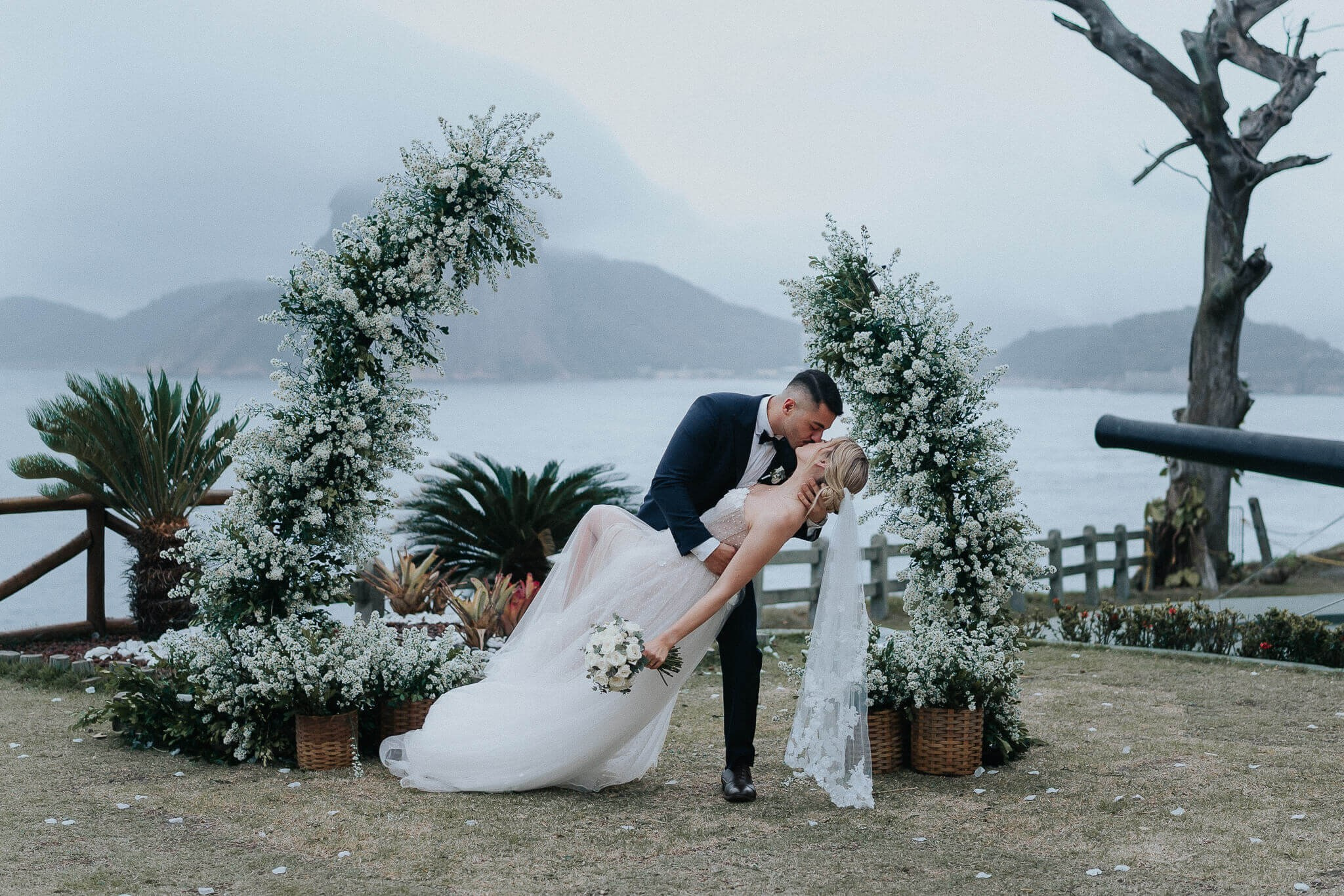 Couple kissing during outdoor wedding ceremony with Sugarloaf Mountain view in Rio de Janeiro, romantic destination wedding in Brazil.