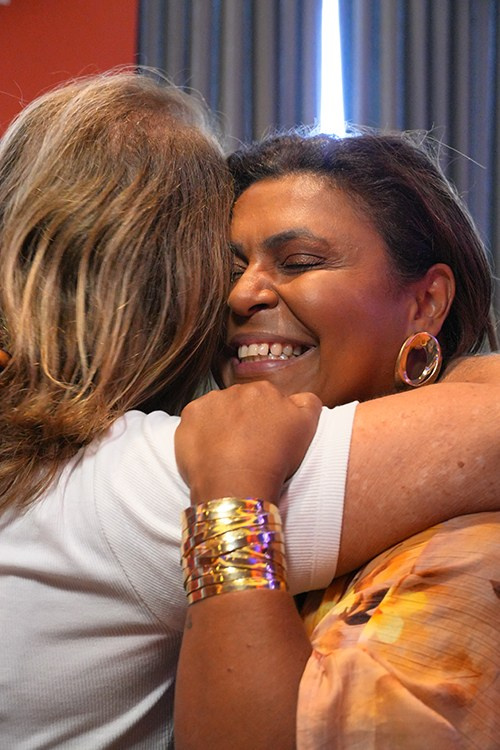 Mulheres se abraçando durante momento descontraído em evento de lançamento da Un1ca