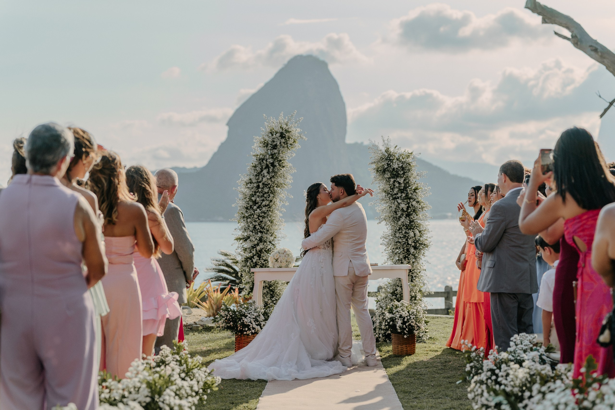 Couple kissing during outdoor wedding ceremony with Sugarloaf Mountain view in Rio de Janeiro, romantic destination wedding in Brazil.