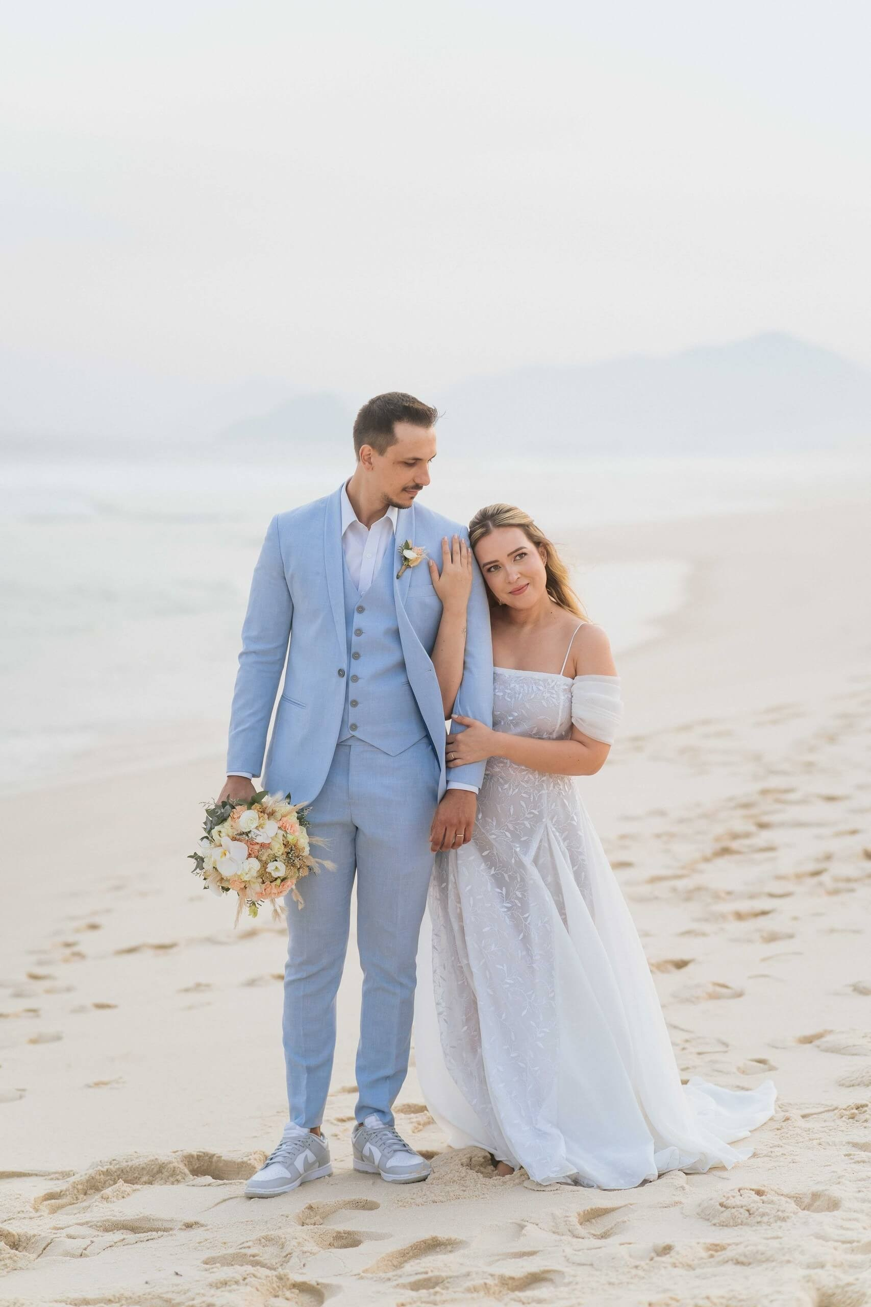 Bride and groom walking on the sand during a romantic beach wedding in Rio de Janeiro, destination wedding in Brazil.