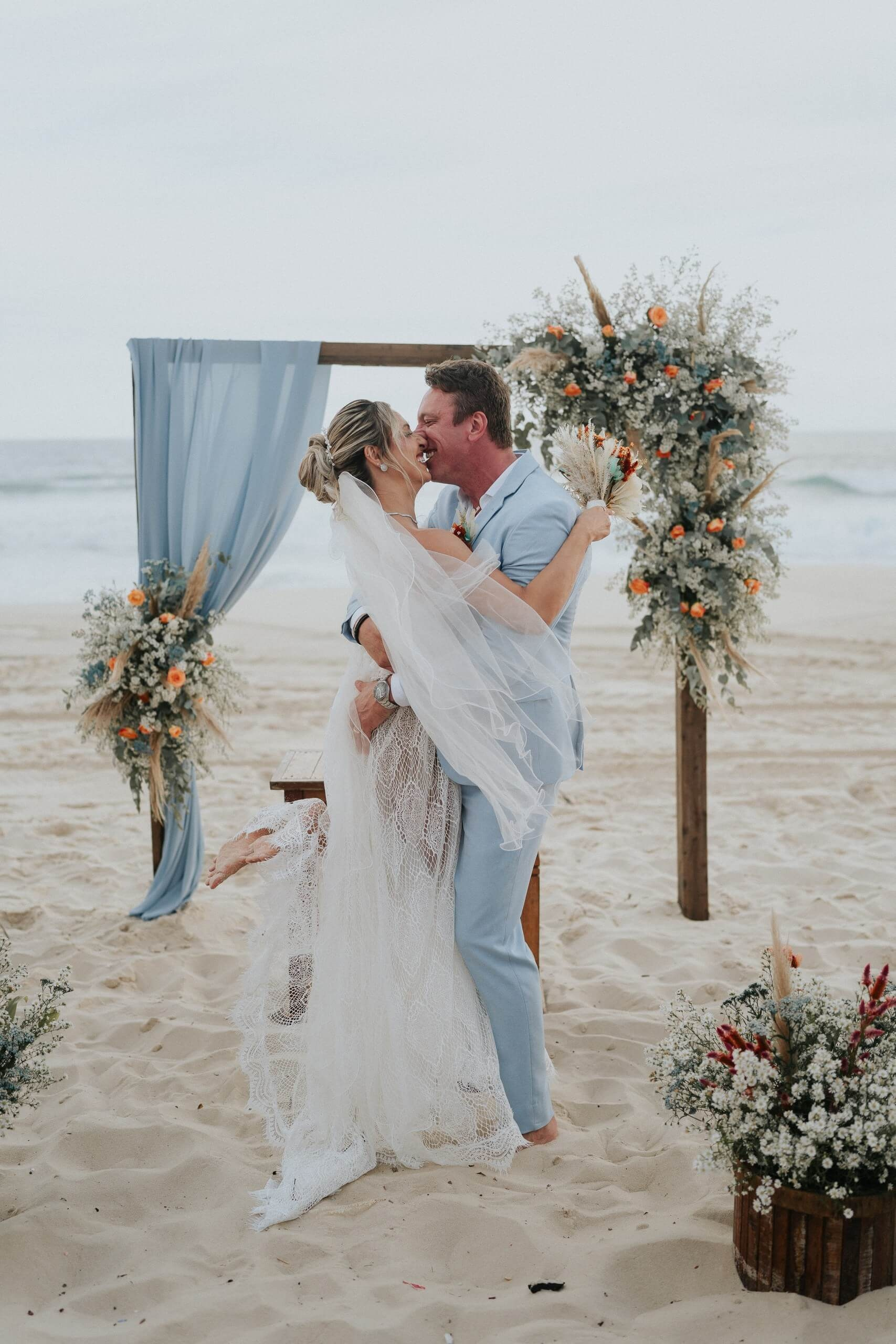 Elegant couple kissing during romantic beach wedding in Rio de Janeiro, unforgettable destination wedding in Brazil.